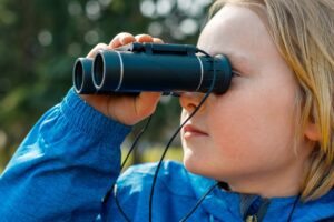 Child looking through binoculars looking for hidden gems in Baton Rouge