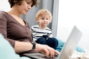little boy watching mom using laptop deciding to buy a home in baton rouge